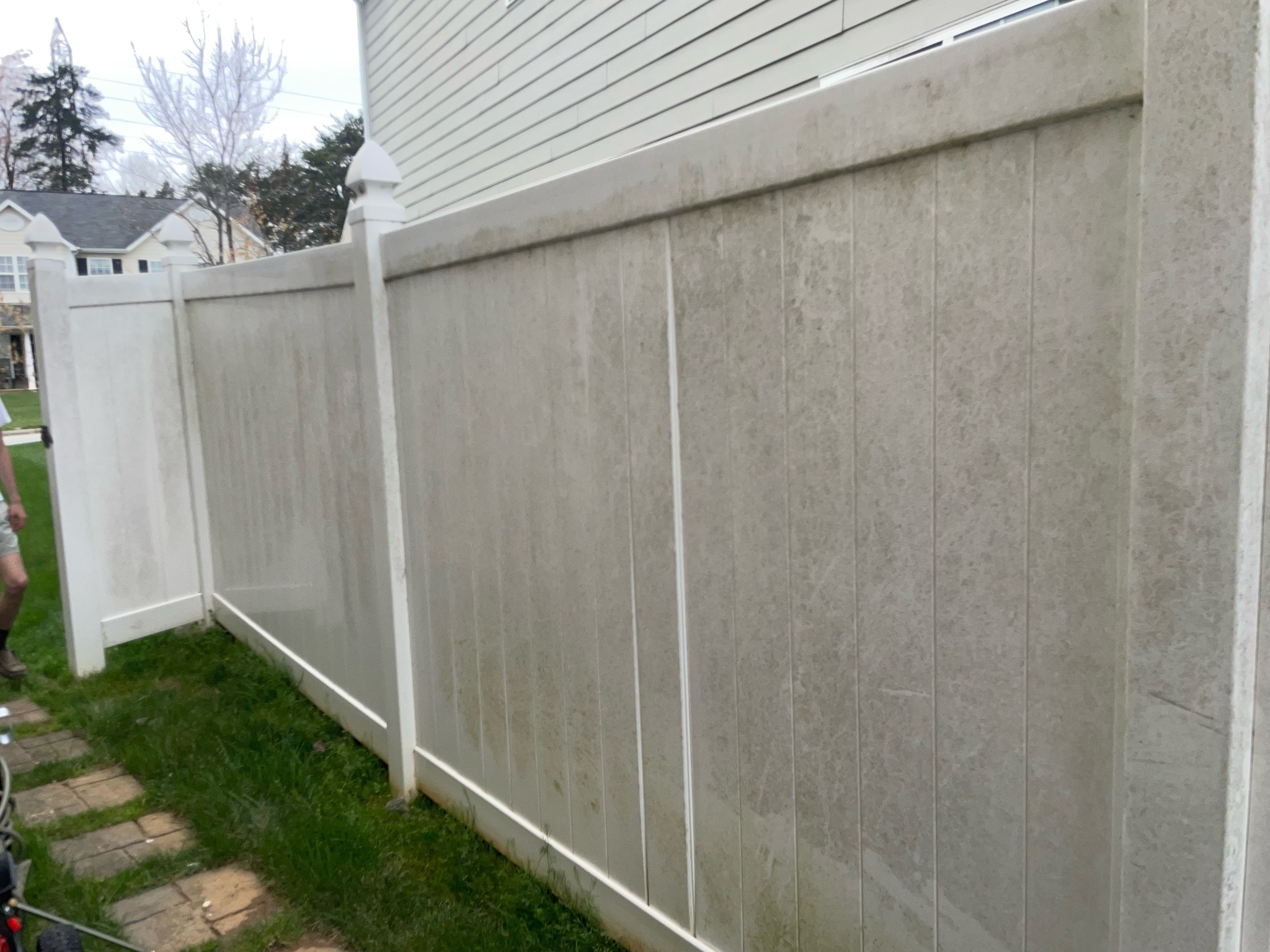 Vinyl fence before pressure washing with visible discoloration and grime